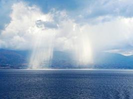 rays of sun breaking through clouds in sea photo