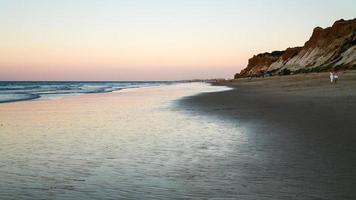 tourists walk on beach Praia Falesia in evening photo