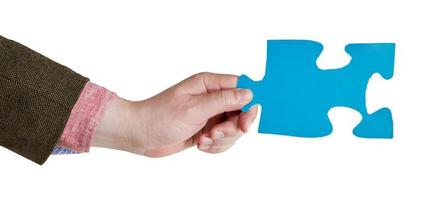 mano masculina sosteniendo una gran pieza de rompecabezas de papel azul foto