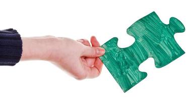 female hand with painted green puzzle piece photo