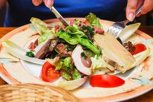 visitor eats salad with Norman meat appetizers photo