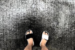 Rainy weather. Child legs in sneakers walking through the rain puddle on the asphalt road, top view. photo