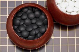 black go stones in wooden bowl on go board photo