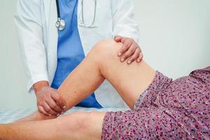 Doctor checking Asian elderly woman patient with scar knee replacement surgery in hospital. photo