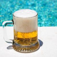 glass with cold light beer on the outdoor pool photo