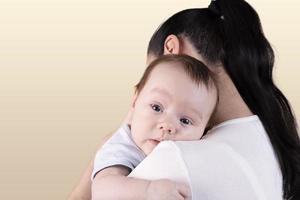 Portrait of a three-month-old baby, boy over mom's shoulder. photo