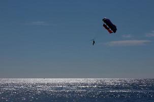 Tourists fly over the sea and the beach on a parachute photo