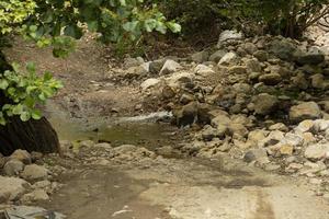 un camino de montaña de tierra y un pequeño río cruzando el camino. fuera del camino. foto