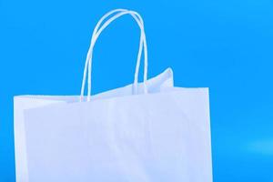 Blank craft bag mockup, mockup of white paper shopping bag with handles on blue background.. photo