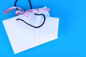 Blank craft bag mockup, mockup of white paper shopping bag with handles on blue background.. photo