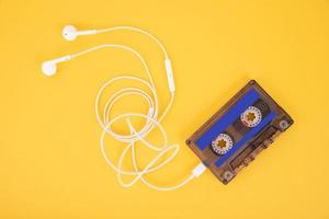 Tape cassette and white headphones. Composition in the form of a player on a yellow background. photo