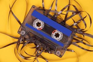 Old cassette tape with unwound tape on a yellow background. photo