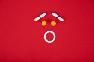 The pills are stacked in the form of a surprised smiley on a red background. Copyspace photo