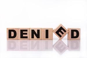 DENIED word, text written on wooden cubes on a white background with reflection. photo