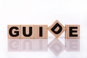 GUIDE word, text written on wooden cubes on a white background with reflection. photo