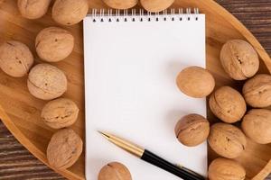 Walnuts and brainstorming, blank notebook on brown background, top view. A copy of the space. photo