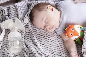 niño adorable, con un juguete favorito, duerme relajado y se recuesta en la cama de los padres foto