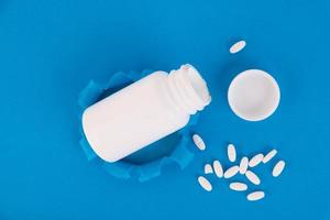 White medical bottle with pills on a blue background. Copy space for text, layout. photo