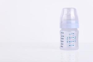 Baby bottle with pacifier and milk for feeding milk on a light background. Copy space. photo