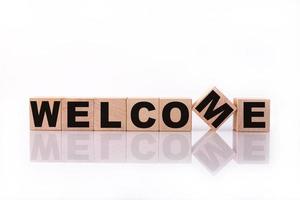 WELCOME word, text, written on wooden cubes, building blocks, over white background with reflection. photo