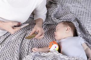 Mom pays online for purchases by phone when the baby is sleeping next to. photo