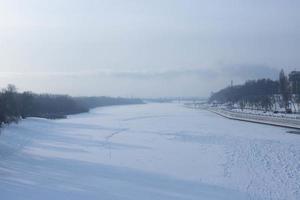 Winter landscape of ice-bound river with frost haze. photo