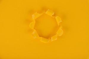 A yellow sheet of paper with a hole in the middle. Background, texture. Copy space. photo