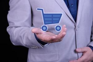 hombre, el hombre de negocios tiene el logo de una cesta de la compra en la mano. icono de carrito de supermercado. comercio minorista tienda minorista en línea. foto