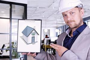 An engineer, a builder in a white helmet looks at the diagrams and drawings inside the premises. photo