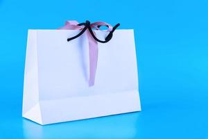 maqueta de bolsa artesanal en blanco, maqueta de bolsa de compras de papel blanco con asas sobre fondo azul.. foto