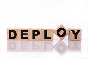 DEPLOY word, text written on wooden cubes on a white background with reflection. photo
