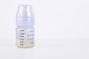 Baby bottle with pacifier and milk for feeding milk on a light background. Copy space. photo