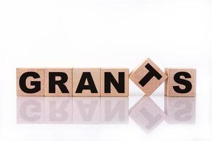 GRANTS word, text written on wooden cubes on a white background with reflection. photo