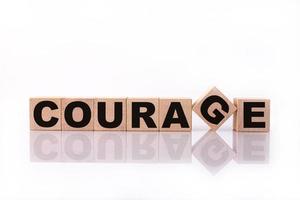 COURAGE word, text, written on wooden cubes, building blocks, over white background with reflection. photo