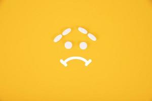 The pills are stacked in the form of a sad smiley on a yellow background. Copyspace photo