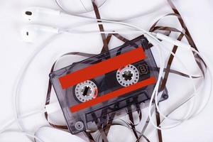 audio cassette with headphones and tangled film lying on a light background. photo