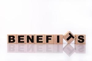 BENEFITS word, text, written on wooden cubes, building blocks, over white background with reflection. photo