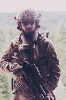 War concept. A bearded soldier in a special forces uniform fighting an enemy in a forest area. Selective focus photo