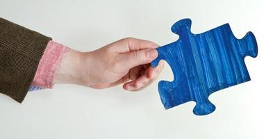 blue painted puzzle piece in male hand photo