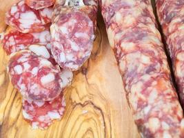 sliced sausage on wooden board close up photo