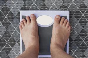 Man is weighed on floor scales standing barefoot photo