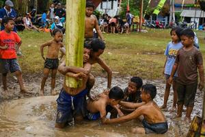 Blitar, Indonesia - September 11th 2022. Several small children who are working together take part in a banana tree climbing competition to commemorate Indonesian Independence in Blitar photo