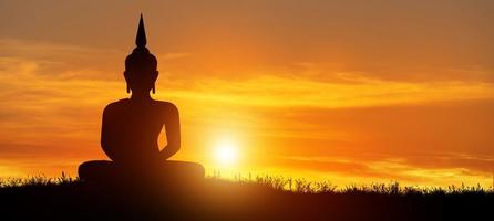 silueta de buda mediando en el crepúsculo con fondo de amanecer. concepto de vacaciones budistas. foto