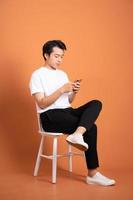 man sitting on chair  isolated on orange background photo