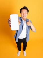 image of asian man holding phone, isolated on yellow background photo