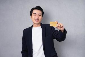 Young business man wearing a suit posing on a grey background photo