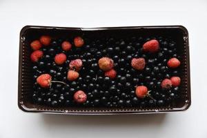 Strawberries and black currants in plastic containers. Delicious fresh berries in a box on a white background. photo
