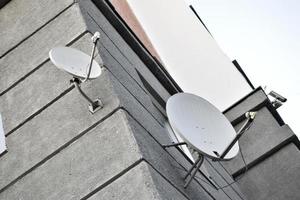 Satellite dish on a gray building close-up. A parabolic antenna on the wall. photo