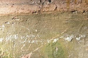 A green broken plastered wall with holes and cracks. photo