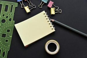 Office still life. Pencil and notepad with paper clips on a black background. photo